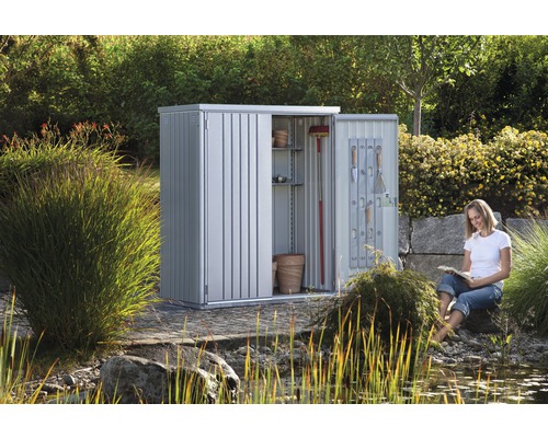 Metall trädgårdsskåp med öppna dörrar och kvinna i trädgården