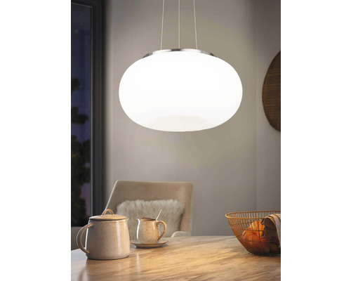 Pendellampa med oval, vit skärm över ett matbord