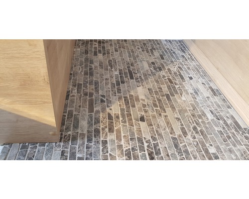 Detaljvy av ett golv med mosaikplattor och ett träskåp