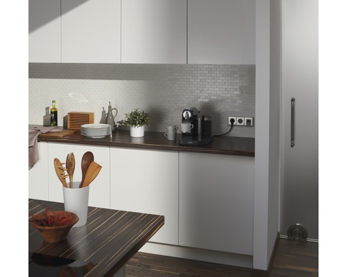 Ljust kök med bänkskiva, köksredskap, kaffebryggare och kaklat stänkskydd