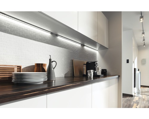 Modernt kök med bänkskiva, porslin, kaffebryggare och underskåpsbelysning