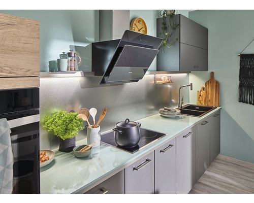 Ljust kök med fläkt, diskho och spishäll.