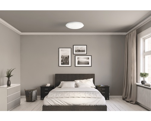 Sovrum med säng, sängbord, byrå och taklampa