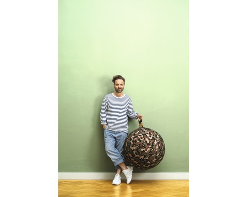 Man lutar sig mot en vägg och håller en rund sittsäck med kamouflagemönster