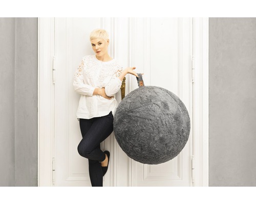 Dekorativ sittpuff i kulform bredvid en kvinna vid en dörr