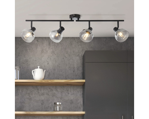 Taklampa med fyra spotlights och klara glasskärmar ovanför hyllor och ett köksskåp