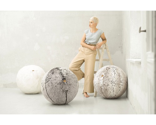 Scen med en kvinna som lutar sig mot en stege och tre runda sittsäckar i vitt och grått