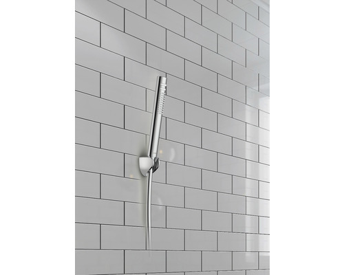 Handdusch med vägghållare framför kakelvägg