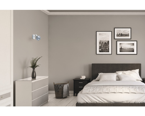 Sovrum med säng, byrå, sängbord, vägglampa och inramade bilder