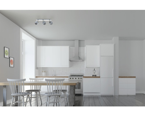 Ljust rum med pentry, matbord och taklampa med tre spotlights.