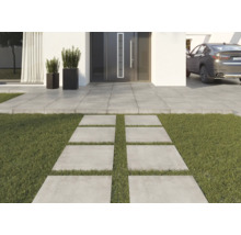 Trädgårdsgång av betongplattor framför ett hus med gräsmatta