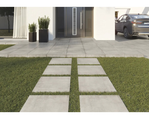 Trädgårdsgång av betongplattor framför ett hus med gräsmatta