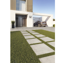 Modern husvy med betongplattor genom gräsmatta och en bil i carporten