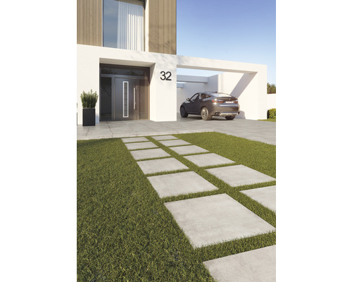 Modern husvy med betongplattor genom gräsmatta och en bil i carporten