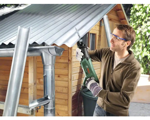 Man skär en takränna med en tigersåg på ett trädgårdsskjul