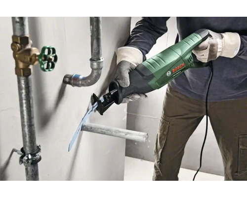 En person sågar ett rör med en tigersåg nära en vattenledning.