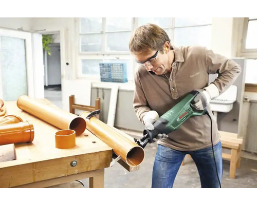 Man sågar plaströr med tigersåg på en arbetsbänk.