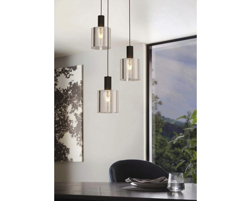 Tre pendellampor av glas och metall hänger över ett matbord