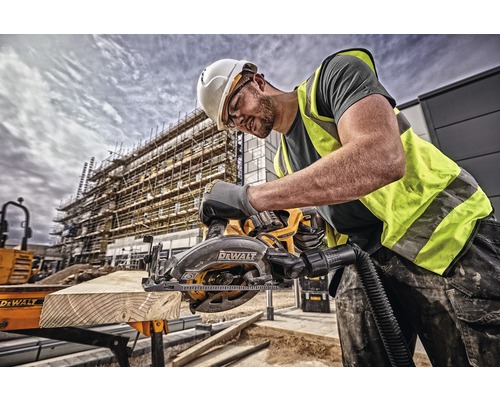 En byggnadsarbetare sågar en träplanka med en DeWalt handcirkelsåg på en byggarbetsplats.