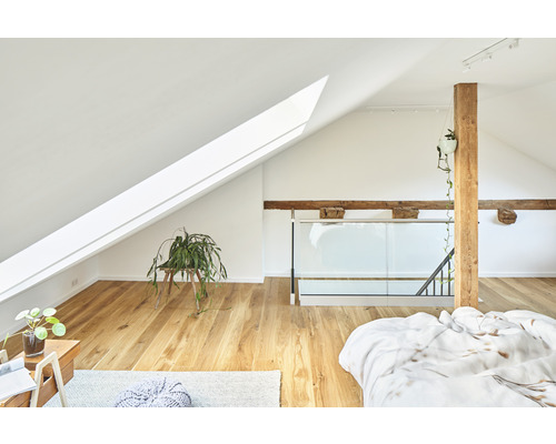 Ljust sovrum på vinden med takfönster, träbjälkar och trägolv