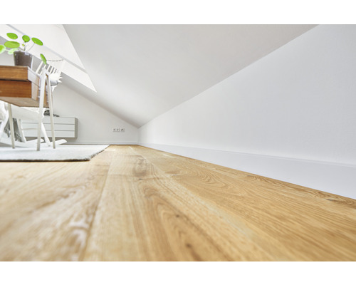 Vindsrum med trägolv, vita väggar och möbler