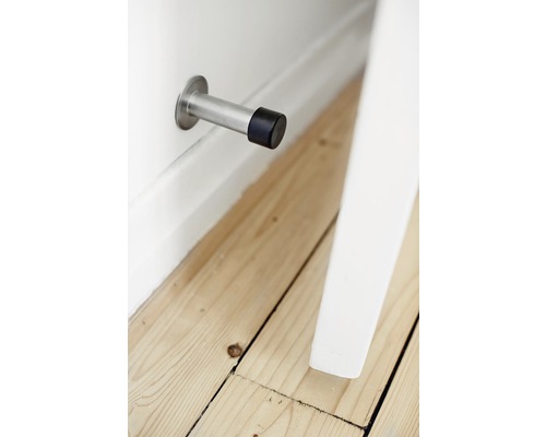 Dörrstopp i metall och gummi monterad på en vägg