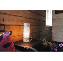 Dekorativ bordslampa med trämönster på ett sidobord i ett rustikt rum.