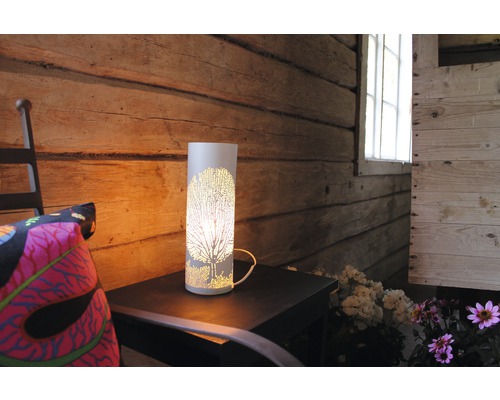 Dekorativ bordslampa med trämönster på ett sidobord i ett rustikt rum.