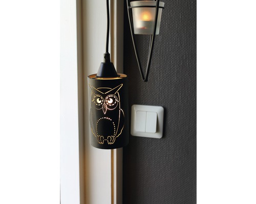 Dekorativ ugglalampa bredvid en väggmonterad värmeljushållare