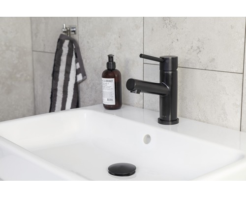 Tvättställ med svart armatur, tvålpump och randig handduk i badrummet