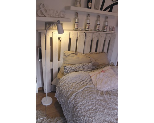 Sovrum med säng, läslampa och dekoration på hyllan