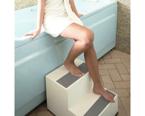 Kvinna med handduk går i badkaret med trappa