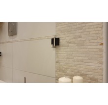 Detaljvy av ett badrum med kakelvägg och sanitetsartiklar
