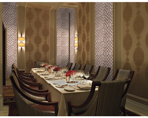 Elegant matsal med mosaikvägg, dekorerad väggpanel, dukat bord och stolar