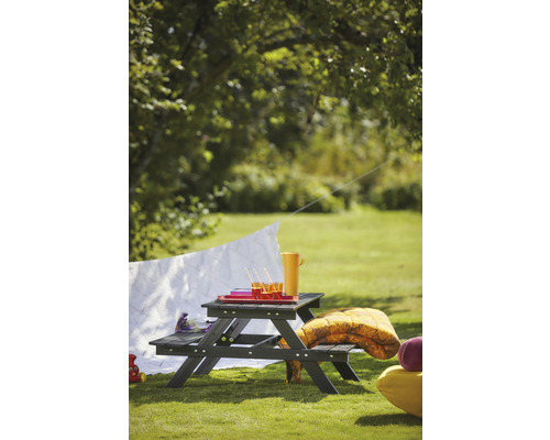 Picknickbord i trä med drycker och filtar i trädgården