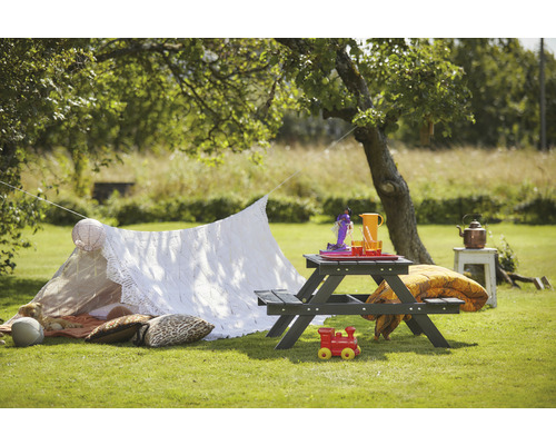 Trädgårdsscen med picknickbord, leksaker och filt under ett träd