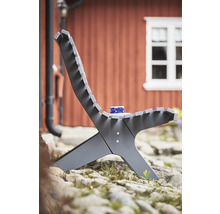 Trädgårdsscen med modern trästol och kopp på stenig mark framför ett hus