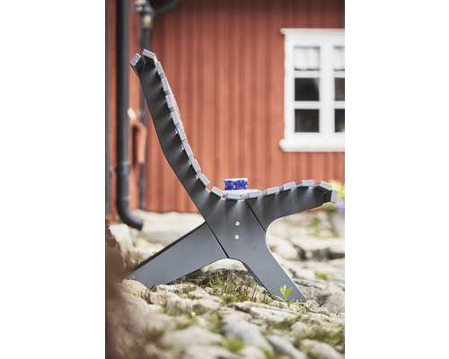Trädgårdsscen med modern trästol och kopp på stenig mark framför ett hus