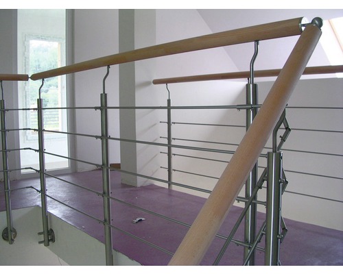 Interiörbild av ett trapphus med räcke i rostfritt stål och trä.