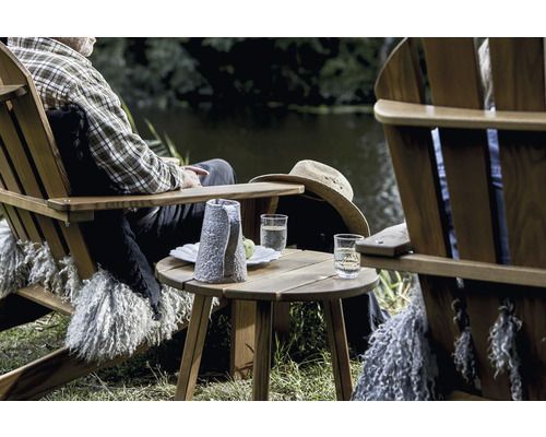 Scen med trästolar, sidobord, drycker och person vid sjön