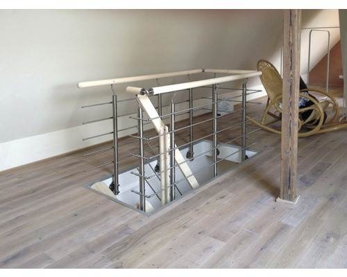 Vy över en trappnedgång med räcke i rostfritt stål i ett rum på vinden