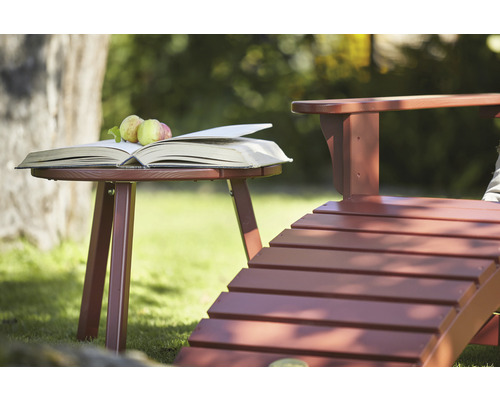 Scen med trädgårdsbord, öppen bok, äpplen och trädgårdsstol utomhus