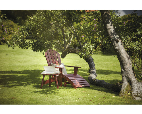 Trädgård med solstol i trä och sidobord under ett träd