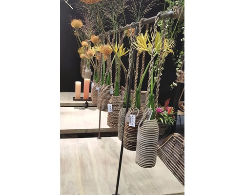 Dekorativa blomsterarrangemang med vaser i flätade korgar på en hängare