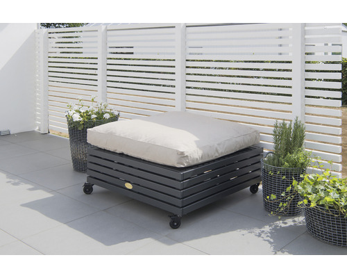 Stoppad pall med hjul på en terrass framför ett vitt staket