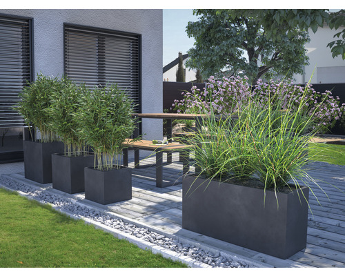 Trädgårdsscen med planterade blomlådor och stenar