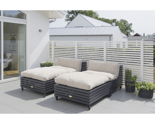 Två solstolar med hjul och dynor på en uteplats med trästaket