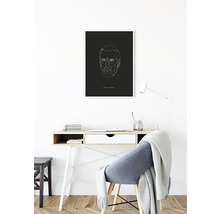 Skrivbord med minimalistiskt porträtt på väggen.