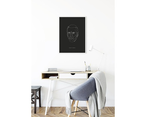 Skrivbord med minimalistiskt porträtt på väggen.