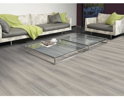 Vardagsrum med laminatgolv, soffa, fåtölj och glasbord.